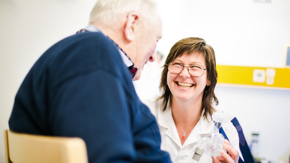 Leende sjuksköterska i möte med en äldre manlig patient