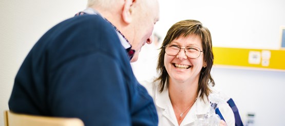 Leende sjuksköterska i möte med en äldre manlig patient